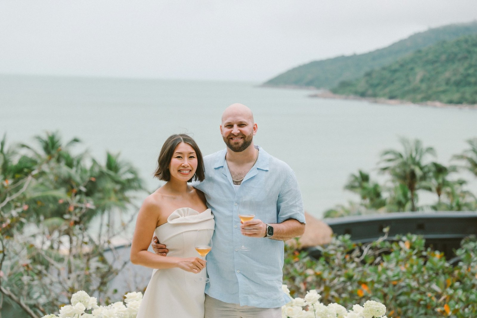 Casal celebrando diante de uma paisagem tropical à beira-mar